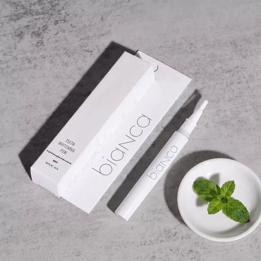 Bianca Advanced Whitening Pen and box on grey concrete with mint in a white dish