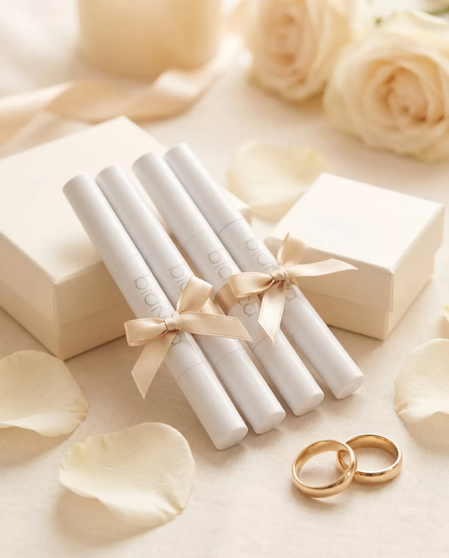 Bridal Party Pens: four Bianca whitening pens tied with champagne ribbons beside gift boxes and wedding bands