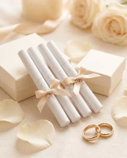 Bridal Party Pens: four Bianca whitening pens tied with champagne ribbons beside gift boxes and wedding bands