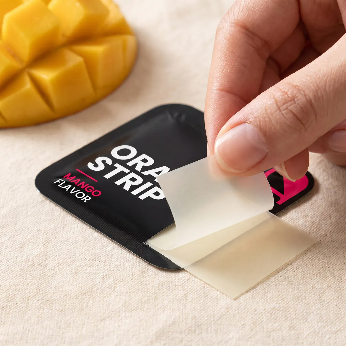 Hand peeling a mango collagen oral strip out of its black packet