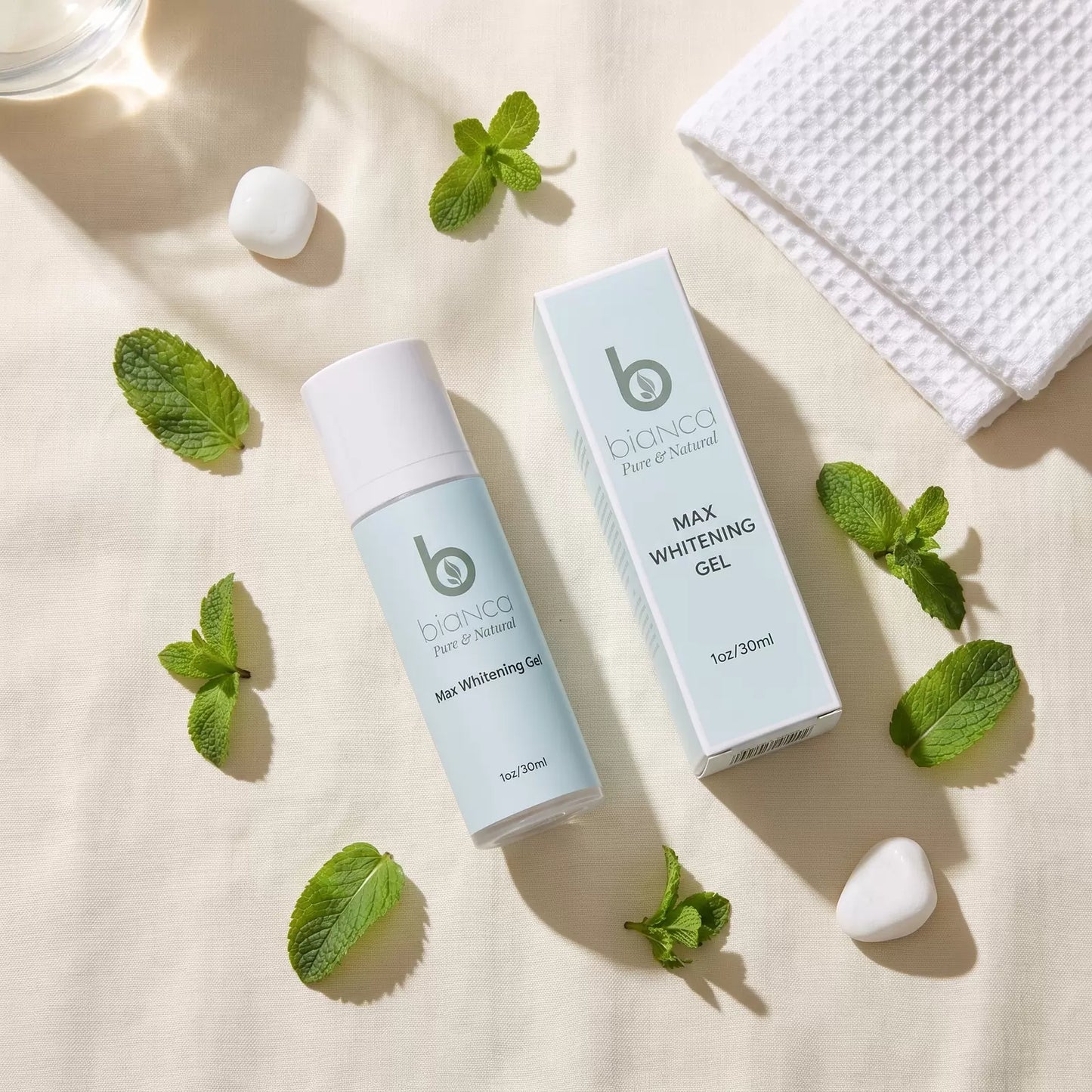 Bianca Pure & Natural Max Whitening Gel bottle and box on cream linen with fresh mint leaves