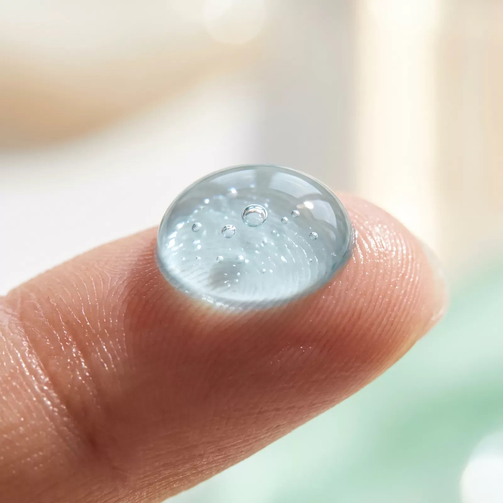 Macro of a clear drop of Bianca Max Whitening Gel on a fingertip showing its lightweight texture