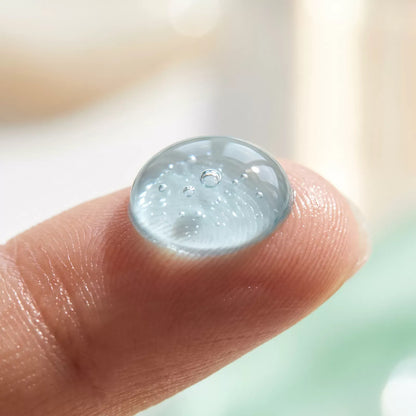 Macro of a clear drop of Bianca Max Whitening Gel on a fingertip showing its lightweight texture