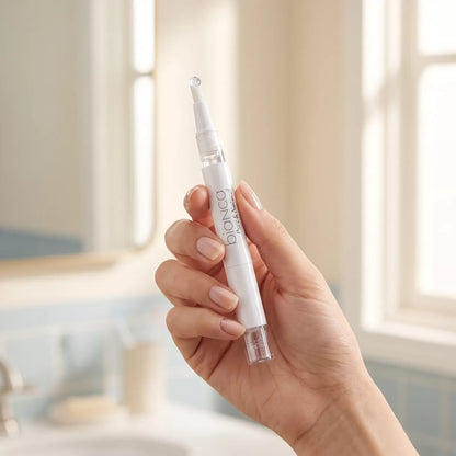 Hand holding the Bianca Pure Whitening Pen with a bead of clear gel on the applicator tip