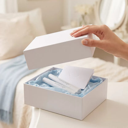 Hand lifting the lid off a Bianca Bright Smile Box revealing whitening pens in blue tissue paper