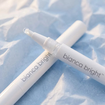 Macro of two Bianca Bright whitening pens crossed on pale blue tissue paper